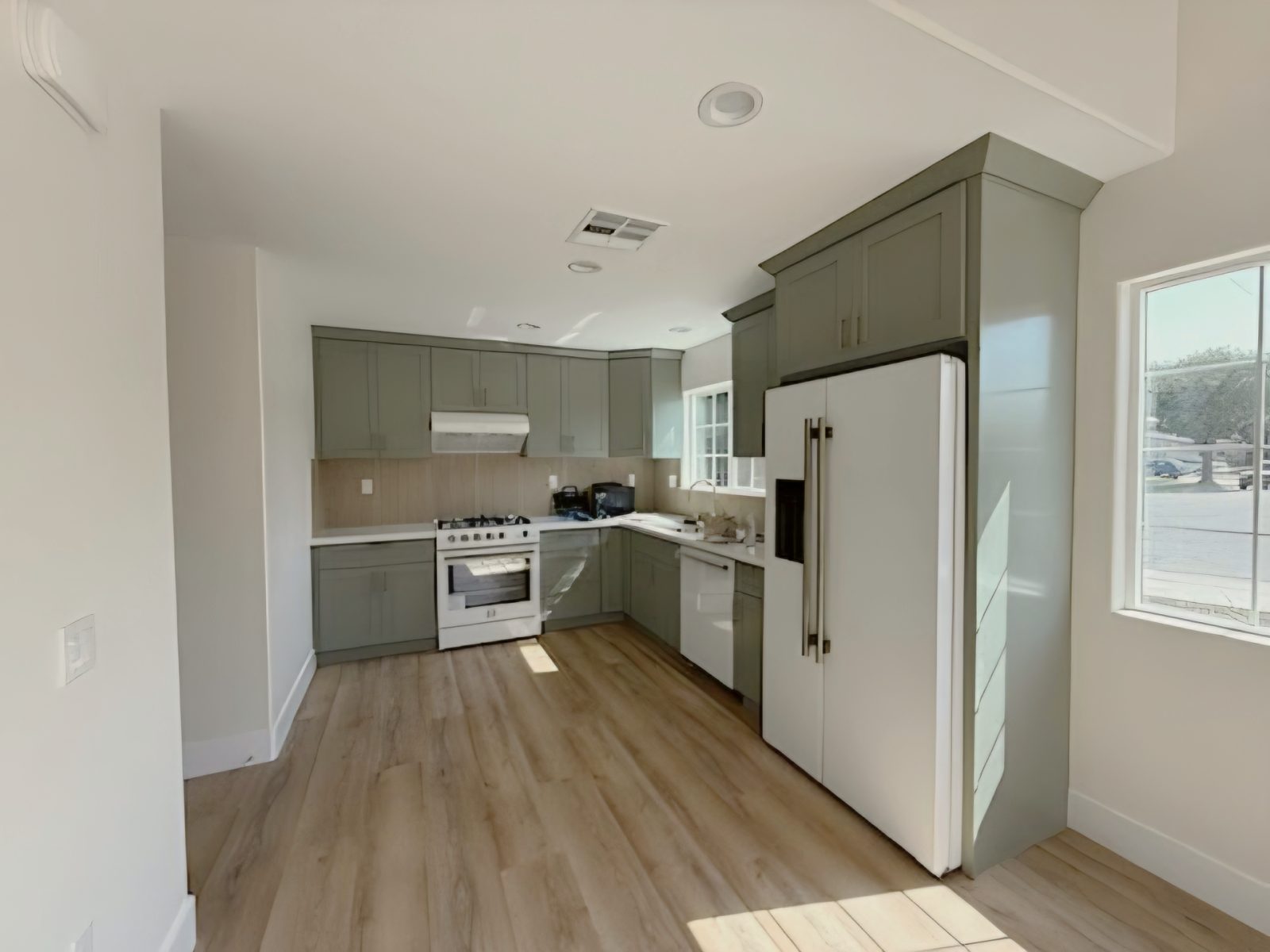 Open kitchen with gray-green cabinets and white refrigerator in an attached ADU in Huntington Beach